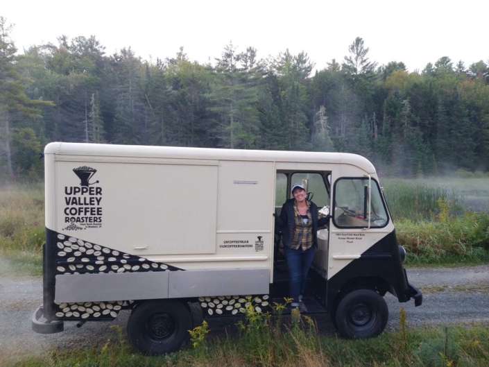 Andrea happy in her coffee truck. Leaving early in the morning fog lifts of the beaver pond with the forest dark in the background.